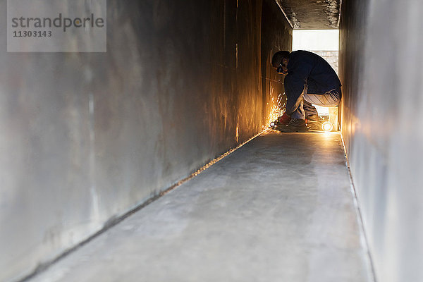 Schweißer mit Schweißbrenner im Stahltunnel