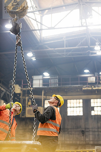 Stahlarbeiter schauen auf die Krankette in der Fabrik