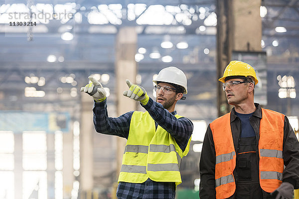 Stahlarbeiter beim Reden und Zeigen in der Fabrik