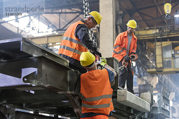 Stahlarbeiter beim Befestigen des Kranhakens am Stahl im Arbeiter