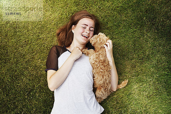 Draufsicht fröhliche junge Frau kuschelnder  liebevoller Hund im Gras