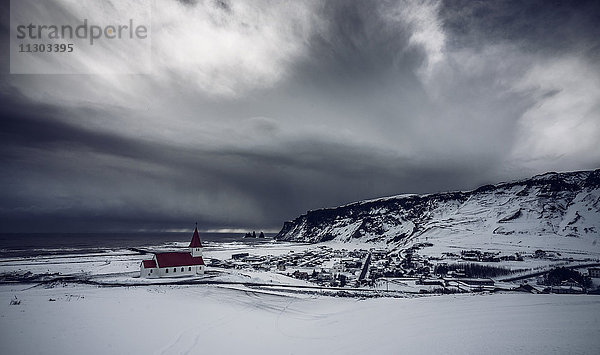 Kirche in abgelegener schneebedeckter Landschaft unter stürmischem Himmel  Vik  Island