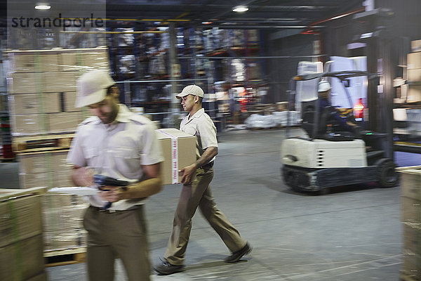Arbeiter tragen und bewegen Kisten mit einem Gabelstapler an der Laderampe eines Vertriebslagers
