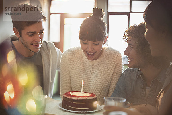 Junge erwachsene Freunde feiern ihren Geburtstag mit Kuchen und Kerzen