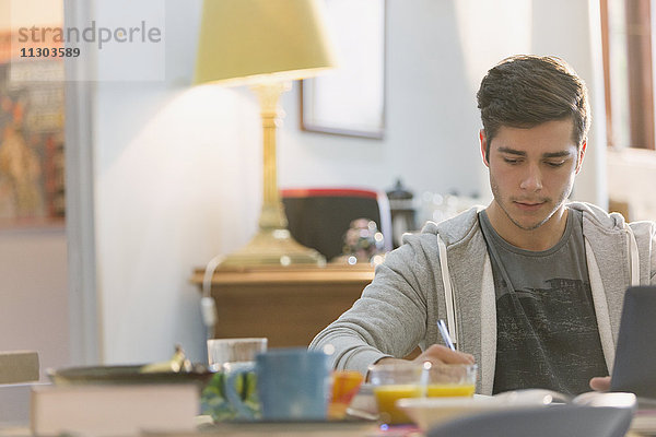 Junger Mann  Student  studiert am Frühstückstisch