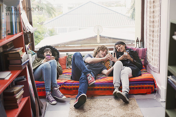 Junge Freunde hängen ab und benutzen Handys im Wohnungsfenster