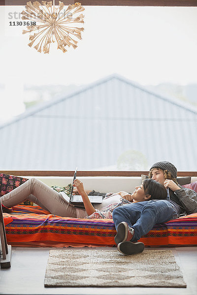 Junges Paar entspannt mit Laptop am Fenster
