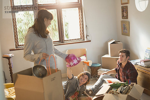 Junge Freundinnen und Freunde packen in der Wohnung aus