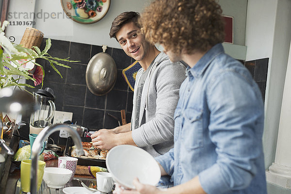 Junge Männer  die in der Küche kochen und abwaschen