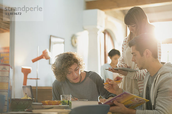 Junge Freunde College-Studenten studieren mit Buch und digitalem Tablet am Tisch