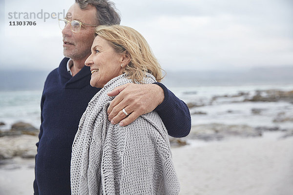 Zärtliches älteres Paar  das sich am Winterstrand umarmt