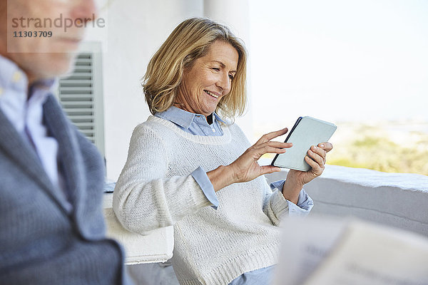Ältere Frau benutzt digitales Tablet auf der Terrasse