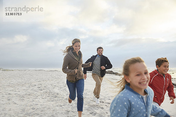 Verspielte Familie beim Laufen am Strand