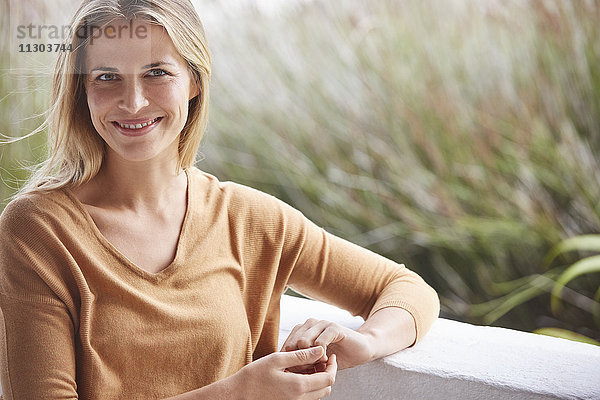 Porträt lächelnde blonde Frau auf Terrasse