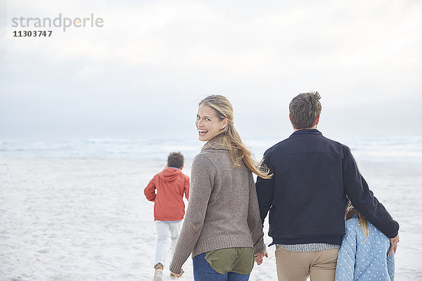 Porträt einer glücklichen Familie  die am Winterstrand spazieren geht