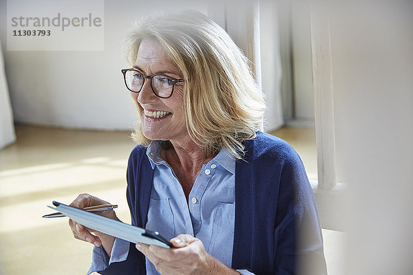 Lächelnde ältere Frau mit digitalem Tablet