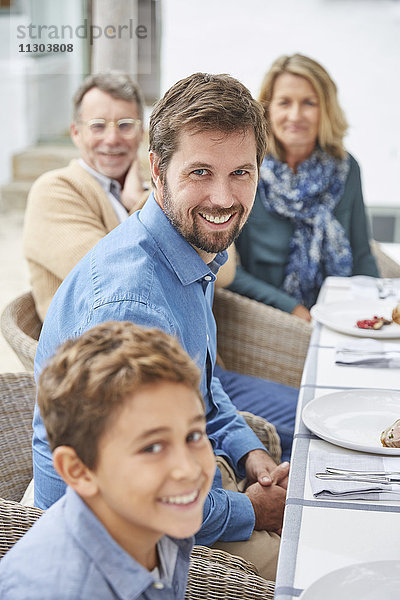 Porträt einer lächelnden Mehrgenerationenfamilie beim Mittagessen im Innenhof