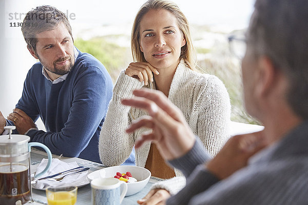 Familie genießt das Frühstück im Gespräch auf der Terrasse