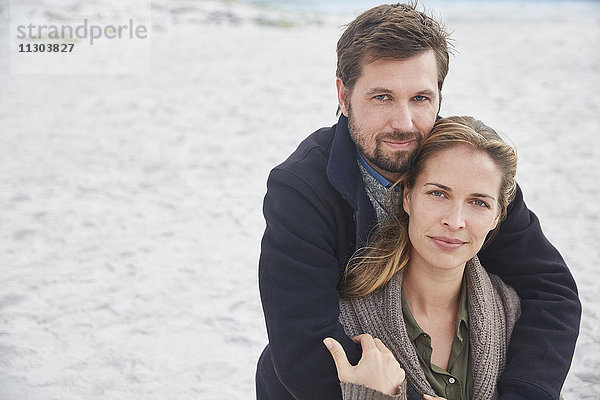 Porträt heiteres zärtliches Paar  das sich am Strand umarmt