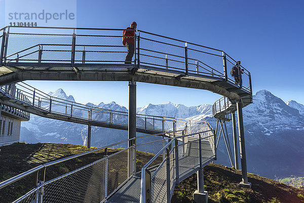 Gipfelweg und Aussichtsplattform mit dem Namen First Cliff Walk auf dem Gipfel des First oberhalb von Grindelwald  Berner Oberland  Schweiz. Die Berge (von links nach rechts): Schreckhorn  Mättenberg  Kleines Fiescherhorn  Grosses Fiescherhorn  Eiger  Jungfrau.