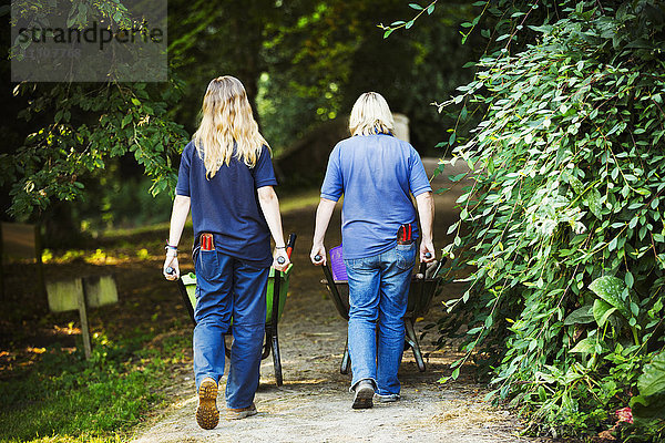 Zwei Gärtnerinnen schieben Schubkarren in Waterperry Gardens in Oxfordshire.