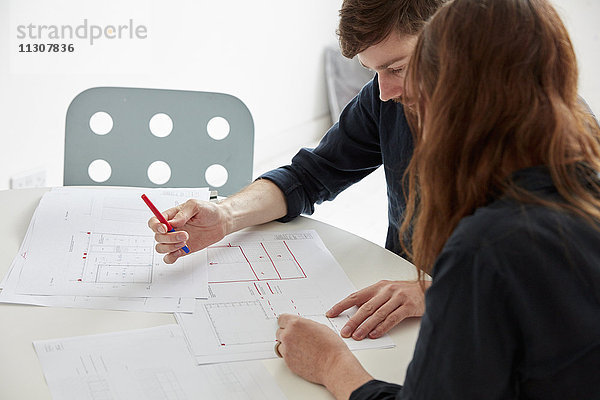 Ein modernes Büro. Zwei Personen bei einem Treffen  bei dem Pläne und Zeichnungen diskutiert werden  Architekturzeichnungen.
