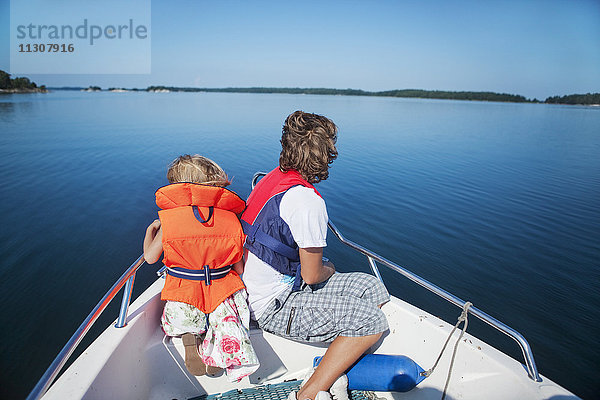 Mittlere erwachsene Frau und Mädchen sitzen auf dem Bug eines Bootes