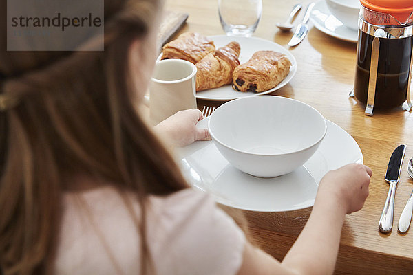 Ein Mädchen deckt den Tisch für das Frühstück.