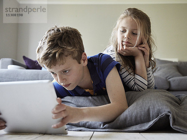 Ein Familienhaus. Ein Junge und seine Schwester schauen sich ein digitales Tablet an.