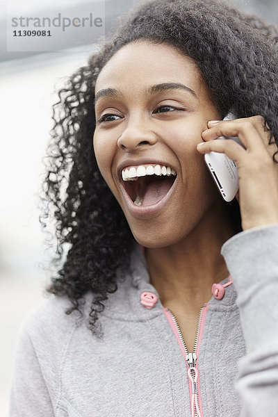Lachende Frau  die über ein Mobiltelefon spricht
