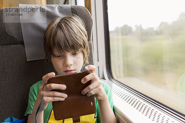 Junge im Zug mit Mobiltelefon