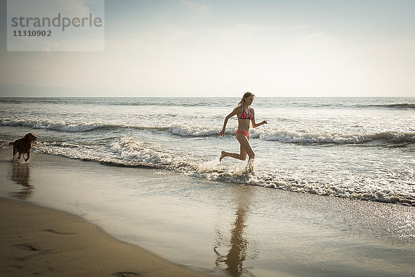 Mexiko  Riviera Nayarit  Frau  die mit Hund am Strand läuft