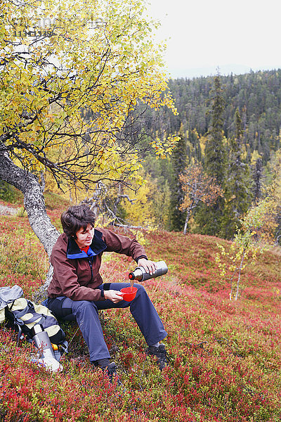 Wanderin gießt Tee in eine Tasse