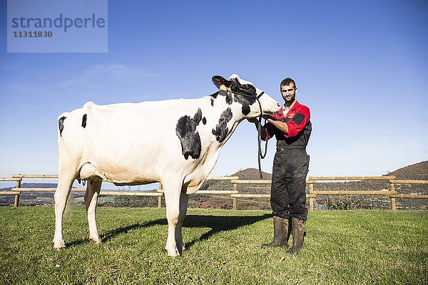 Porträt eines Bauern mit Kuh auf der Weide