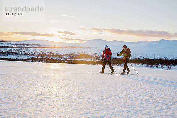 Menschen beim Skifahren bei Sonnenuntergang