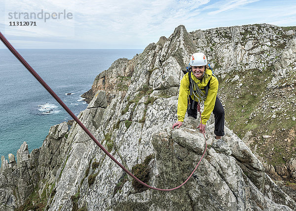 UK  Cornwall  lächelnde Frau beim Klettern auf dem Commando Ridge