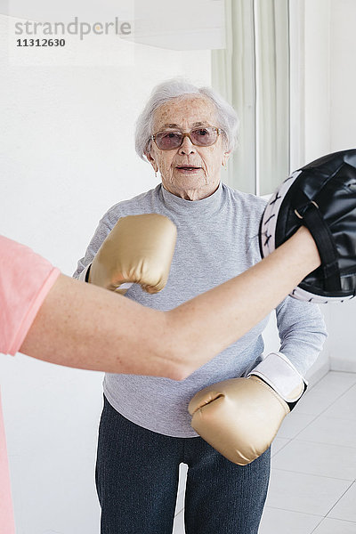 Ältere Frau beim Boxen mit Fitnesstrainerin