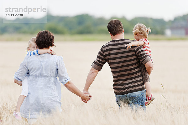 Familie mit zwei Kindern beim Spaziergang im Feld