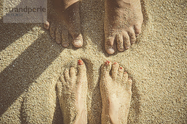 Füße eines im Sand stehenden Paares von oben gesehen