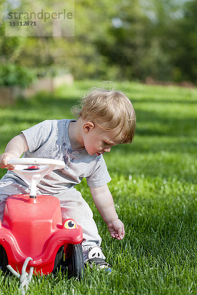 Junge berührt Gras im Garten