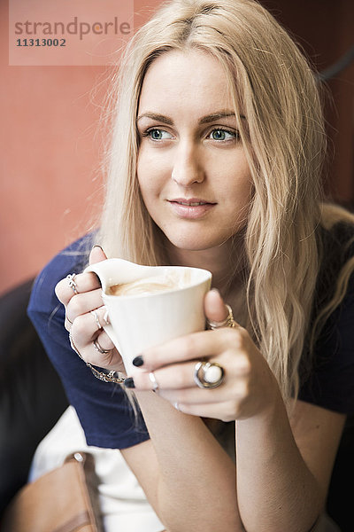 Junge blonde Frau trinkt Kaffee