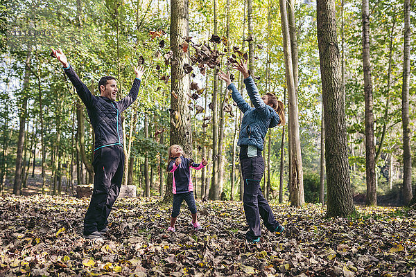 Glückliche Familie wirft Herbstlaub in die Luft
