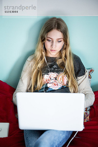 Junge Frau mit Laptop auf dem Bett