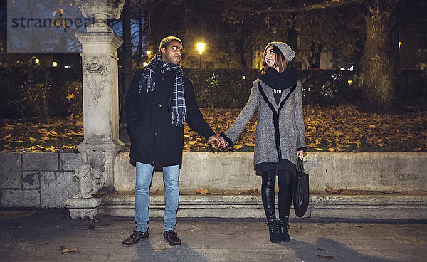 Ein glückliches junges Paar  das sich anschaut  während es Händchen hält.