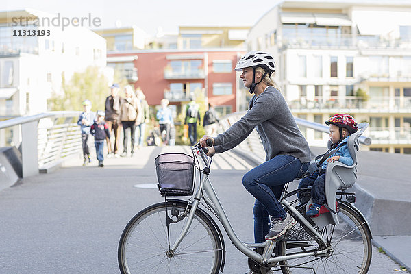 Frau fährt Fahrrad mit Sohn auf dem Rücksitz