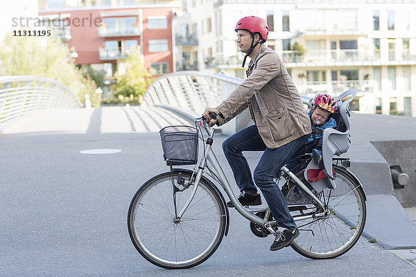 Mann fährt Fahrrad mit Sohn auf dem Rücksitz
