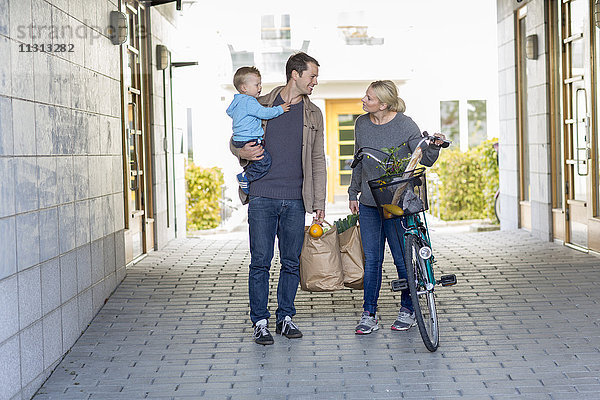 Eltern mit kleinem Jungen beim Spaziergang nach dem Einkaufen