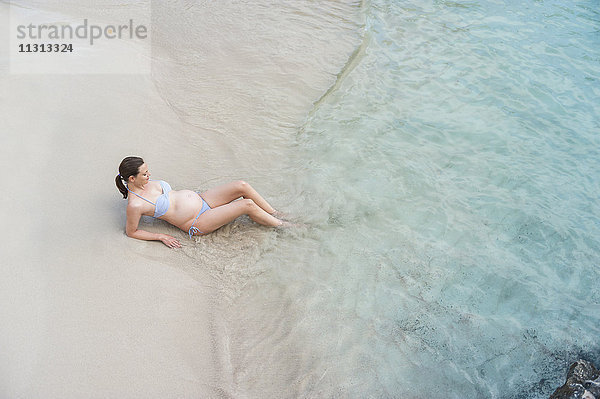 Schwangere Frau am Meer sitzend