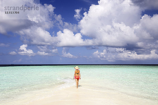 Malediven  Gulhi  Frau  die auf einer Sandbank im flachen Wasser läuft.