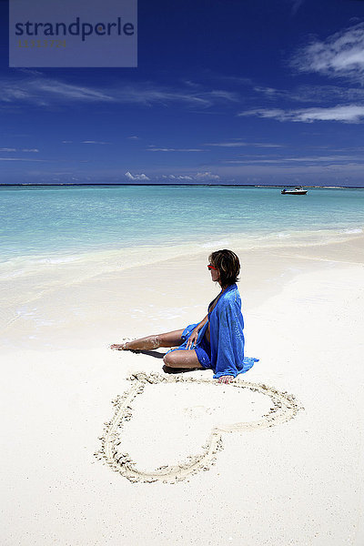 Malediven  Frau am Strand im flachen Wasser sitzend